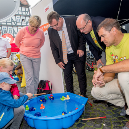 Minister Grüttner (2. v.r.) und Fritzlars Bürgermeister Hartmut Spogat (1. v.r.) sehen beim Entenangeln zu